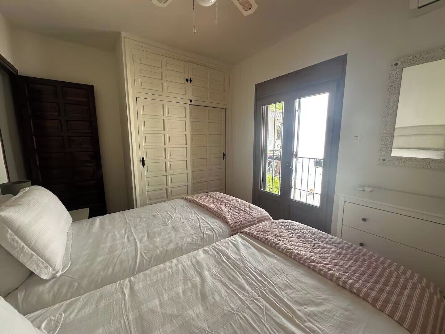 Un dormitorio con una cama, un armario, una puerta con ventana y un espejo en la pared.