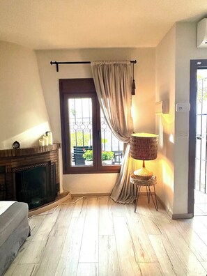 A room with a fireplace, a window with curtains, a lamp, and a door.