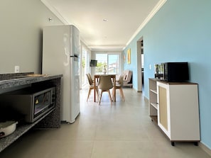 Eine moderne Küche mit Kühlschrank, Mikrowelle und Backofen. Es gibt einen Essbereich mit Tisch und Stühlen.