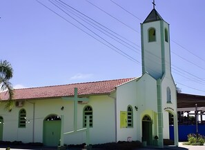 A church with a bell tower, a red roof, and a green door.