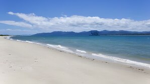 A beach with a clear sky and mountains in the distance.