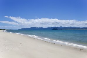 A beach with a clear sky and mountains in the distance.
