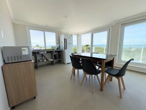 Eine moderne Küche mit Essbereich, großen Fenstern und Blick ins Freie.