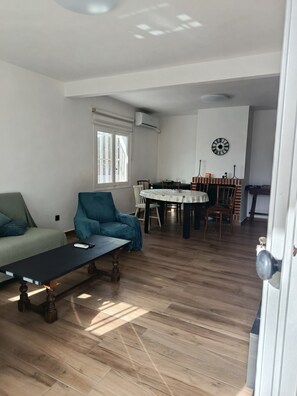 A living room with a sofa, armchair, and a coffee table. There is a dining area with a table and chairs. - Wonderful Villa with Private Pool and Barbecue (Alicante (Alacant))