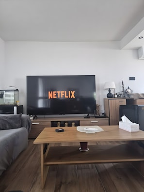 A living room with a large flat-screen TV displaying 'NETFLIX,' a wooden coffee table, a sofa, and a small cabinet. - Wonderful Villa with Private Pool and Barbecue (Alicante (Alacant))