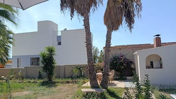Un patio con un edificio blanco, palmeras y una zona de estar.