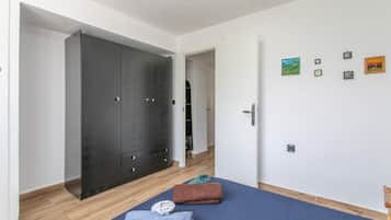 Een kamer met een grote kast, een bed met handdoeken, en een wand met ingelijste foto's.