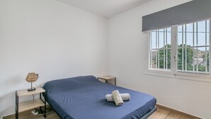 A bedroom with a single bed, a small bedside table, a lamp, and a window with a view of greenery. - Villa 'Espectacular chalet con piscina privada y barbacoa cerca de Alicante , san juan y el Campello' (Alicante (Alacant))