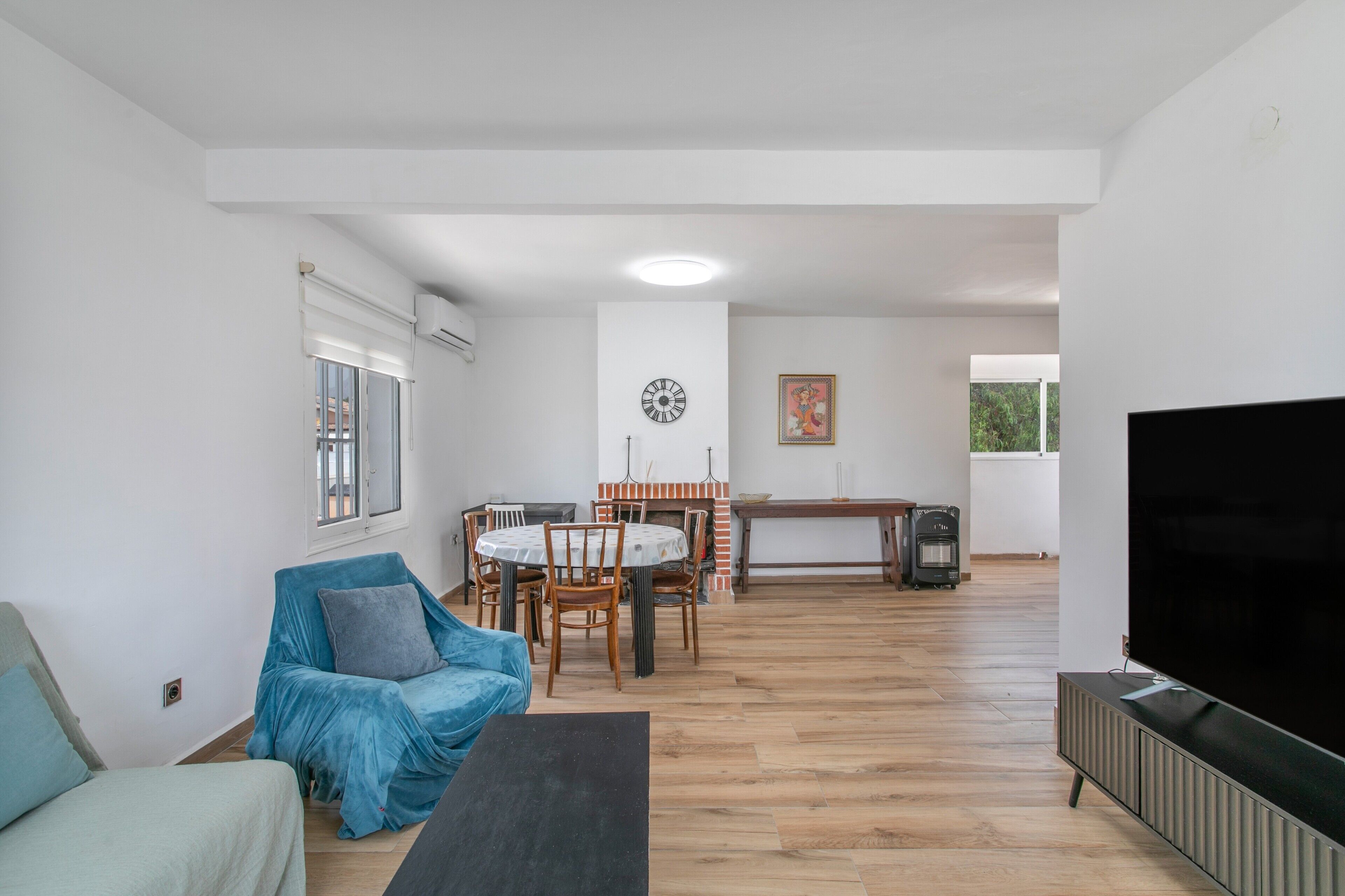 A living room with a sofa, a TV, a dining area with chairs and a table, and a fireplace.