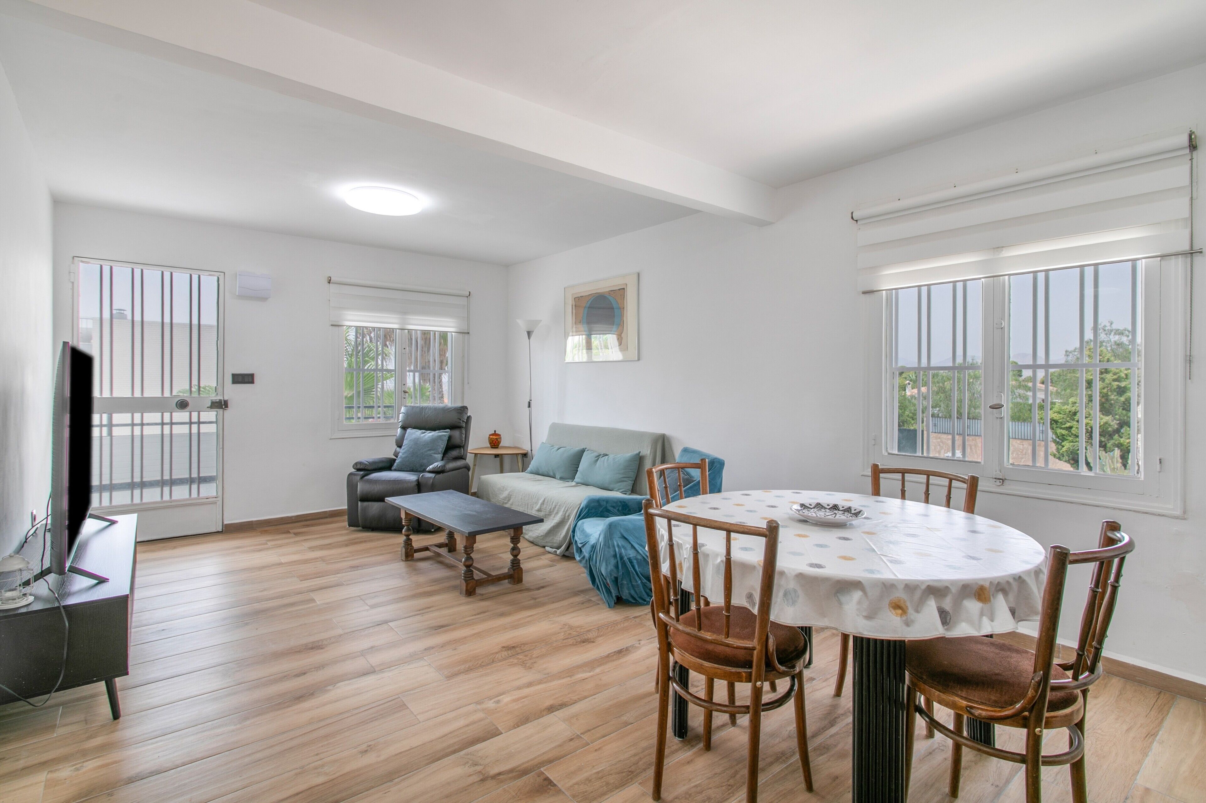 Un salón amplio con mesa de comedor, sillas, sofá y televisor.