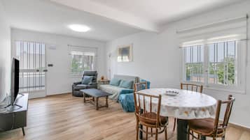 Un salón amplio con mesa de comedor, sillas, sofá y televisor.