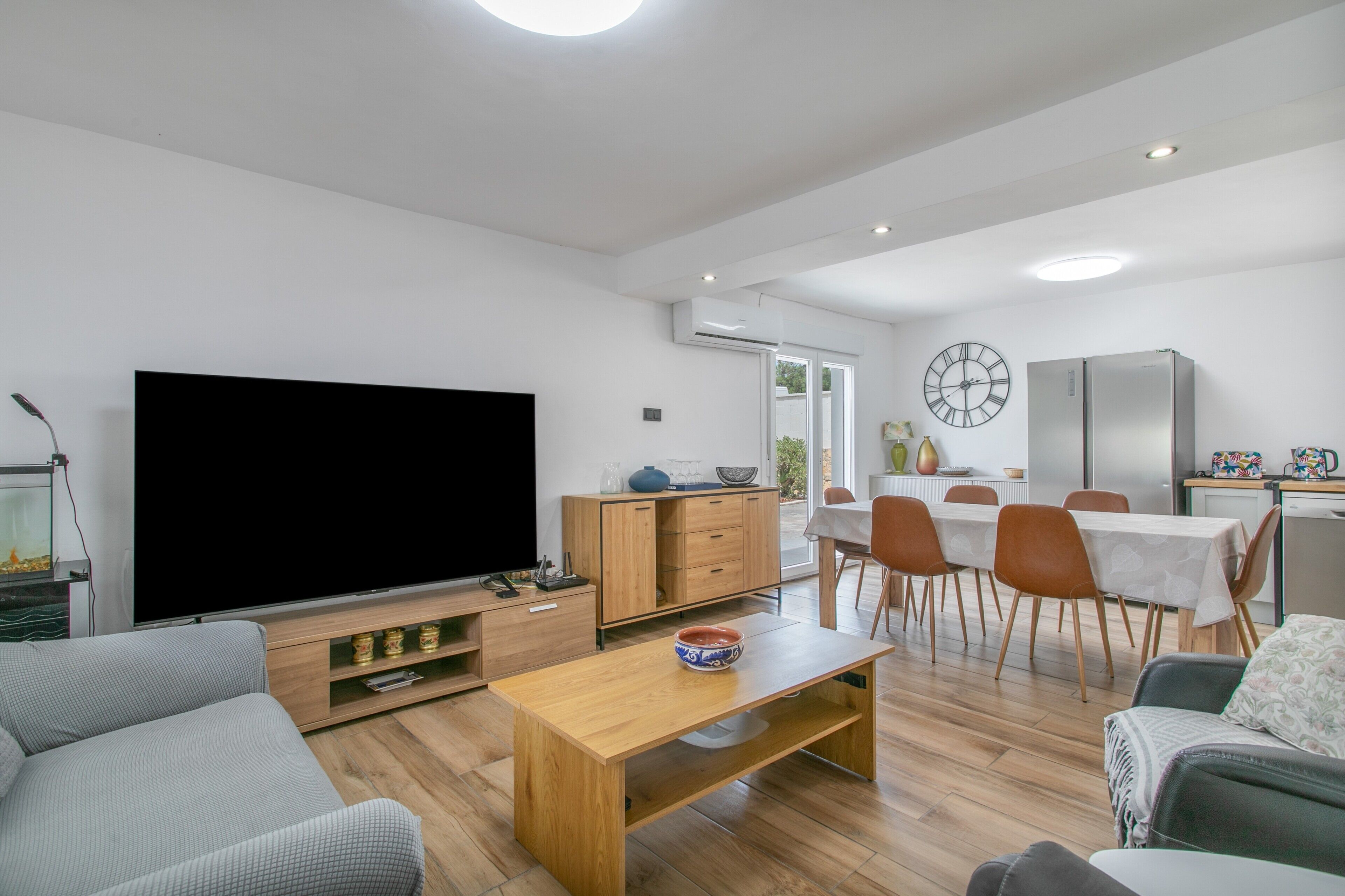 Un soggiorno moderno con una televisione a schermo piatto, un tavolino in legno e un divano.