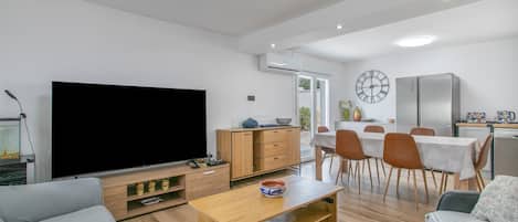 Ein modernes Wohnzimmer mit Flachbildfernseher, Couchtisch aus Holz und einer Couch.