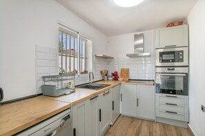 A modern kitchen with white cabinets, a wooden countertop, a built-in oven, and a window.