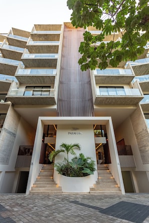 A modern building with a central staircase, a sign reading 'PARA LA', and a planter with plants at the entrance. - Great studio, close to the supermarket, Fifth Avenue, and the beach. (Playa del Carmen)