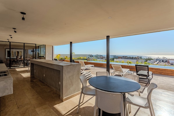 A modern outdoor dining area with a view of the cityscape. - Great studio, close to the supermarket, Fifth Avenue, and the beach. (Playa del Carmen)