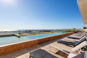 A rooftop pool with lounge chairs and a view of the ocean. - Great studio, close to the supermarket, Fifth Avenue, and the beach. (Playa del Carmen)