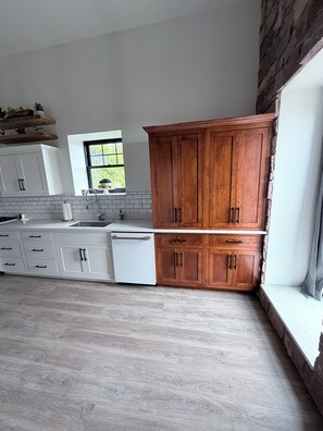 Een moderne keuken met witte kasten, een ingebouwde vaatwasser en een groot raam dat voor natuurlijk licht zorgt.