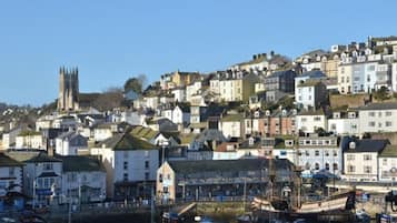 A coastal town with a prominent church tower, residential buildings, and a waterfront area with boats.