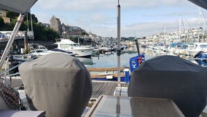 Un puerto deportivo con barcos amarrados, un edificio al fondo y una zona cubierta con asientos.