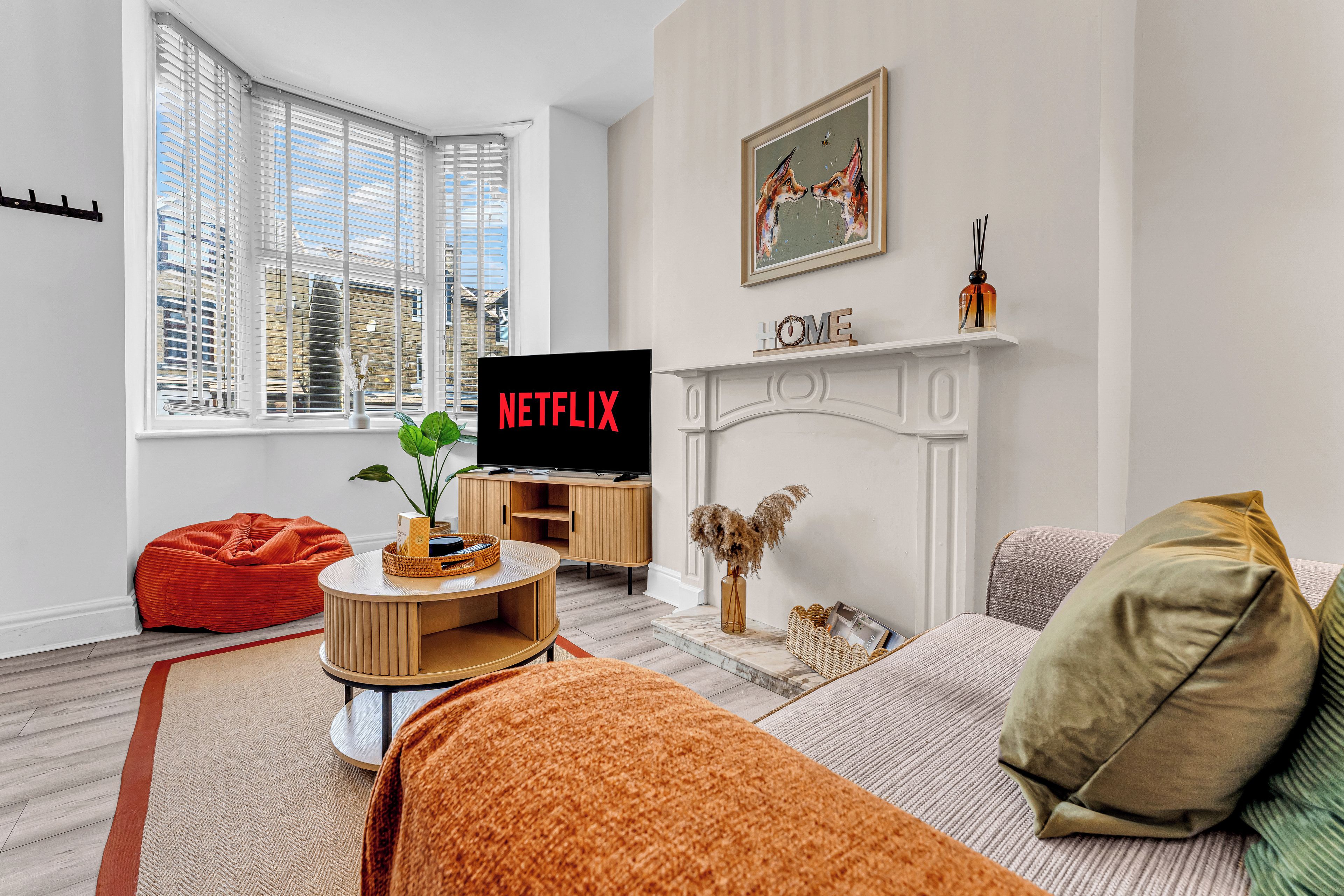 Un salon avec une télévision, une cheminée et une grande fenêtre.