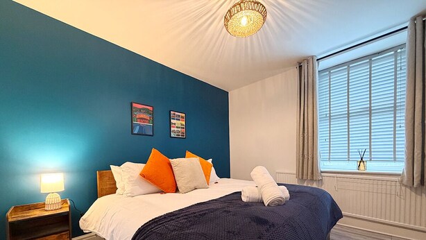 A bedroom with a bed, a nightstand, a lamp, a window with curtains, and a wall with two framed pictures. - Peak Side Terrace, 3BR, Sleeps 5 - Buxton (Buxton)