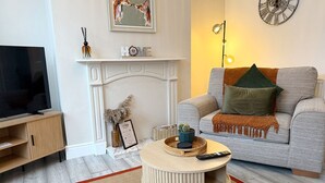 A living room with a television, a fireplace, a sofa, and a round coffee table. - Peak Side Terrace, 3BR, Sleeps 5 - Buxton (Buxton)