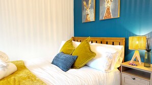 A hotel room with a bed, a nightstand, a lamp, and two paintings on the wall. - Peak Side Terrace, 3BR, Sleeps 5 - Buxton (Buxton)