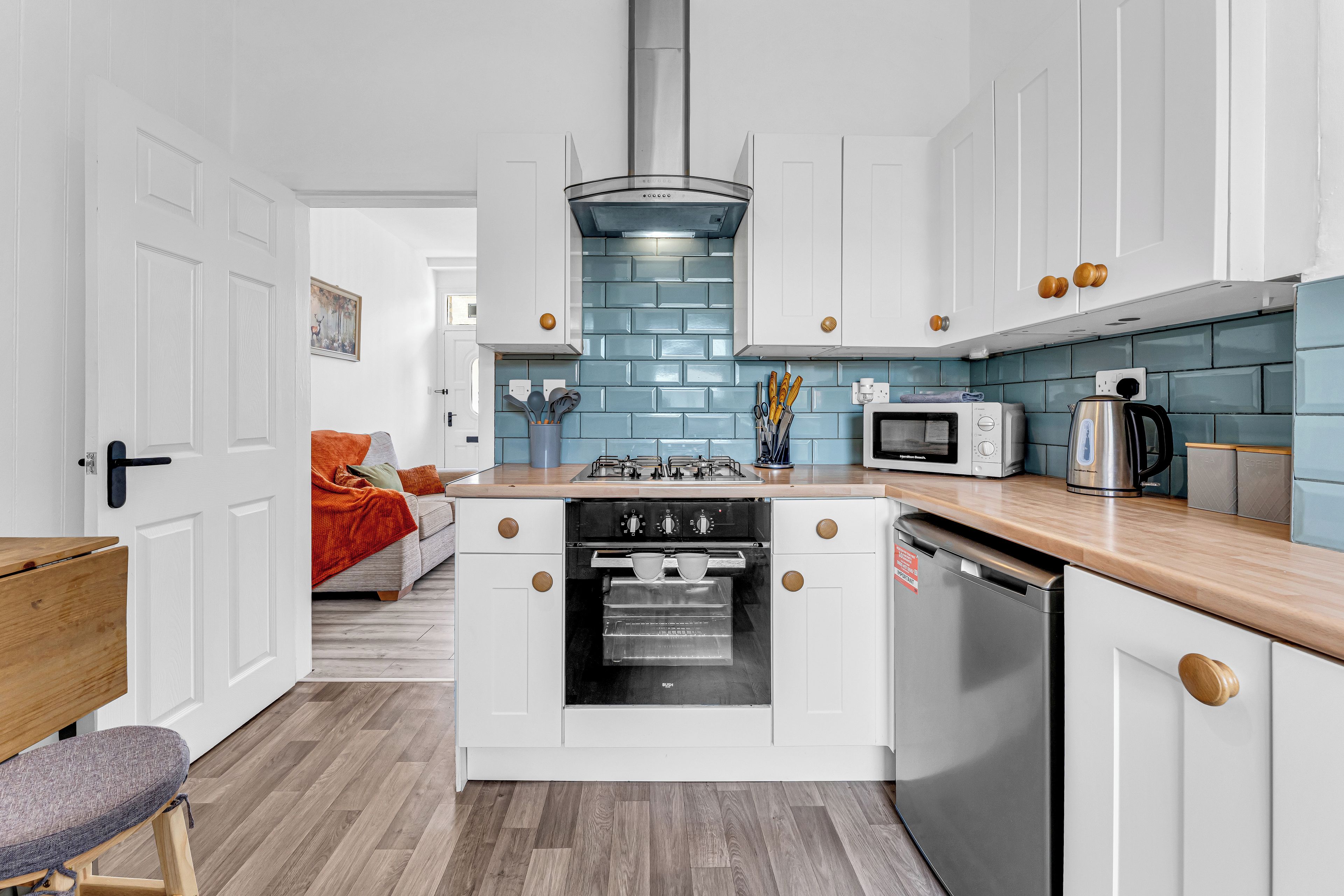 A compact kitchen with white cabinetry, a central island with a stove, and a dishwasher.