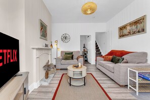 Un salon moderne avec une cheminée, un ensemble de canapés, une table basse et un téléviseur.