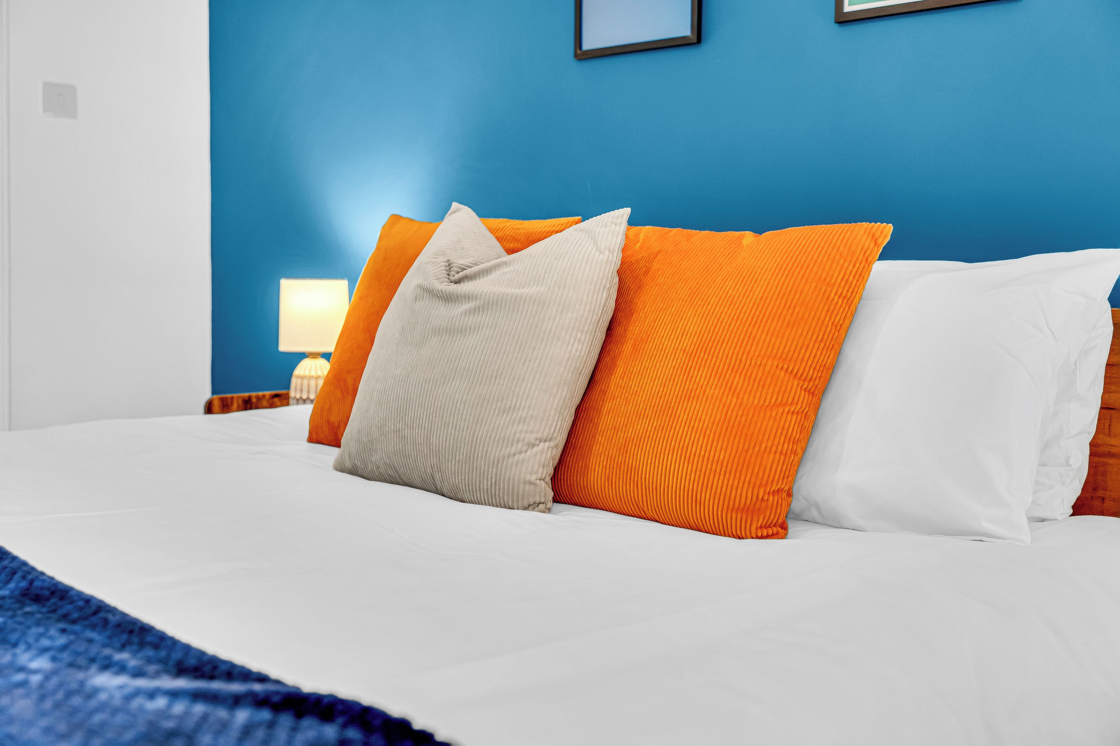 Un lit avec une literie blanche et plusieurs oreillers de différentes couleurs.
