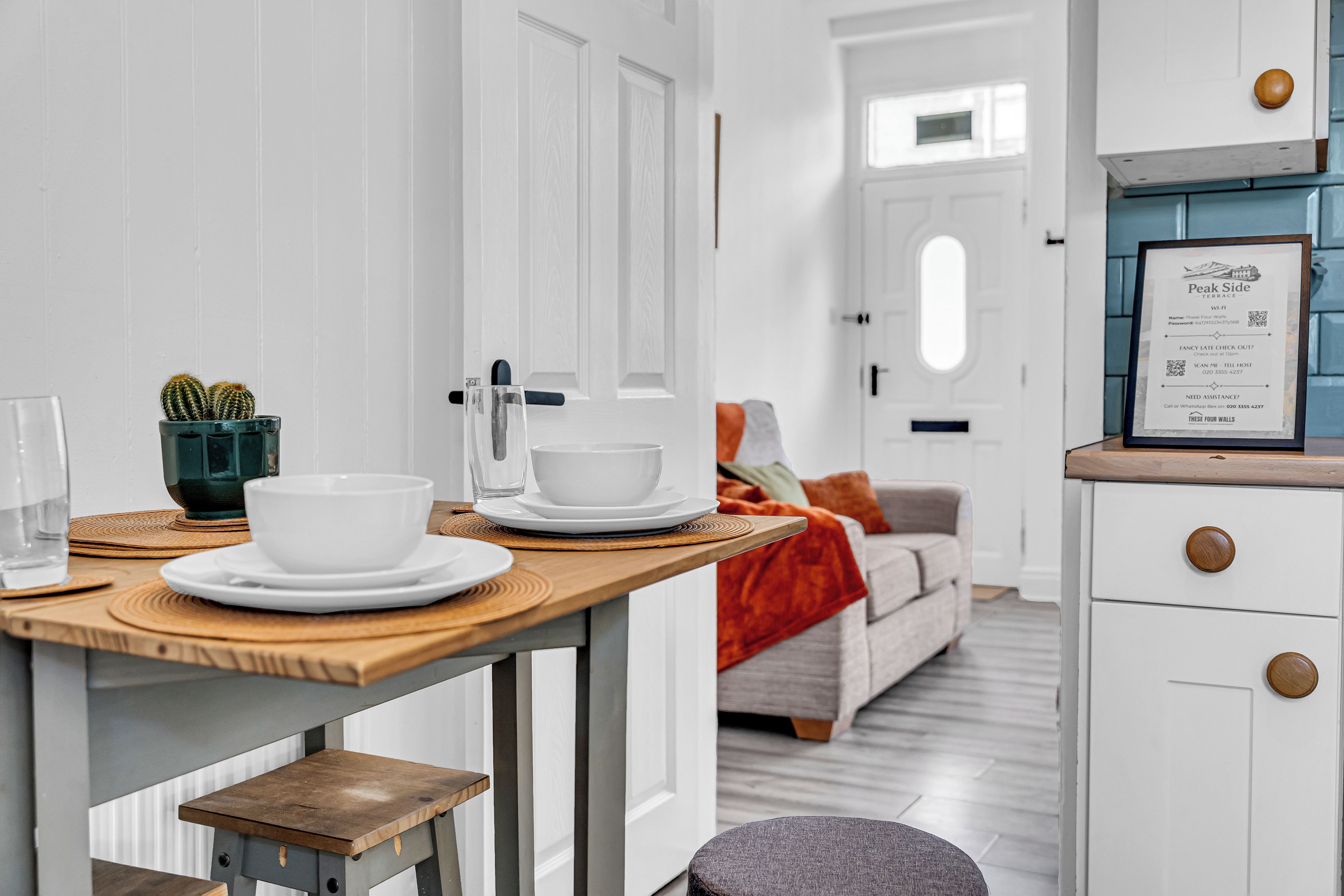 A modern kitchen with white cabinetry, a wooden countertop, and a dining area with a table set for two.