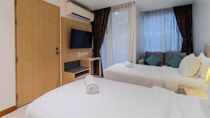 Habitación de hotel con dos camas, televisión, aire acondicionado y armario de madera.