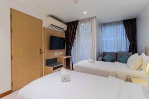 Ein Hotelzimmer mit zwei Betten, einem Fernseher, einer Klimaanlage und einem Holzschrank.