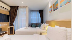 Una habitación de hotel con dos camas, televisión, escritorio y obras de arte en la pared.