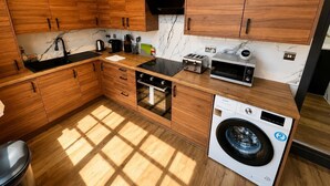 Uma cozinha moderna com armários de madeira, forno embutido, micro-ondas, torradeira e máquina de lavar.