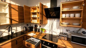 Uma cozinha moderna com armários de madeira, bancada preta, forno embutido, micro-ondas e máquina de café.