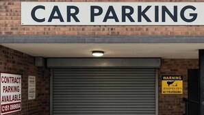 A car parking area with a closed garage door, a warning sign, and a contract parking availability sign.