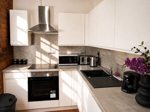 A modern kitchen with white cabinets, stainless steel appliances, and a Bosch coffee maker. - City Centre | Sleeps 6 | Bars, Parking & Netflix (Merseyside)
