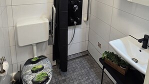 Ein Badezimmer mit Toilette, Dusche, Waschbecken und Spiegel.