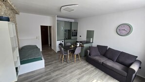 Ein kompakter Wohnbereich mit Küchenzeile, Essbereich, einer Couch und einem Bett.