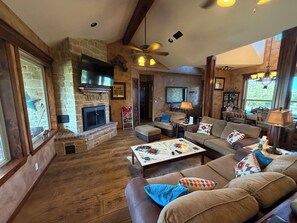 A cozy living room with a stone fireplace, leather sofas, a coffee table, and a television. - Hidden Gem: Private 3BR Retreat in Cross Plains (Cross Plains)