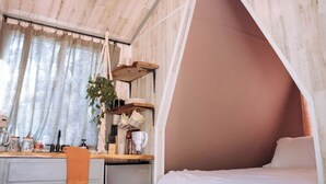 Una habitació acollidora amb un llit, un escriptori i una planta penjant.
