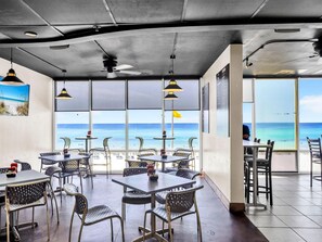 A restaurant with tables and chairs, large windows with a view of the beach, and ceiling fans. - Tidewater 2315 (Panama City Beach)