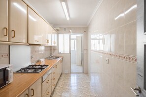A kitchen with a stove, microwave, and cabinets. - GuestReady - Vialia apartment next to the station (Málaga)