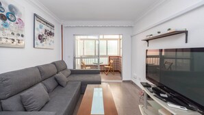Ein Wohnzimmer mit grauem Sofa, Fernseher und Couchtisch aus Holz.