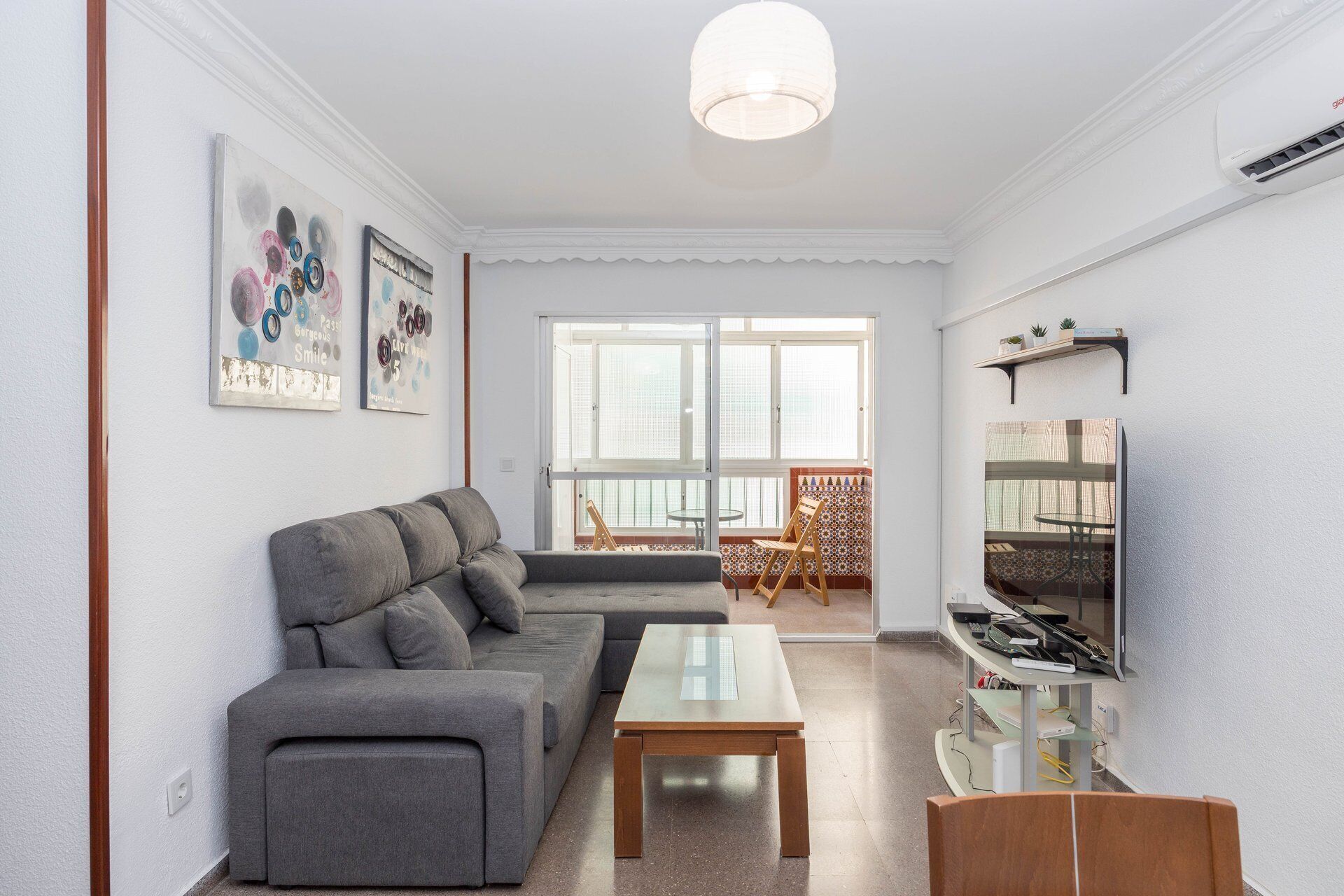 Una sala de estar con un sofá, una mesa de centro, un televisor y obras de arte en la pared.