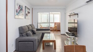 Ein Wohnzimmer mit einer Couch, einem Couchtisch, einem Fernseher und Bildern an der Wand.