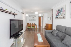 A living room with a TV, sofa, coffee table, and dining area with chairs. - GuestReady - Vialia apartment next to the station (Málaga)