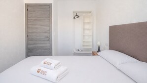 Ein Hotelzimmer mit Bett, Kleiderschrank, Kleiderständer und Nachttisch mit Lampe.